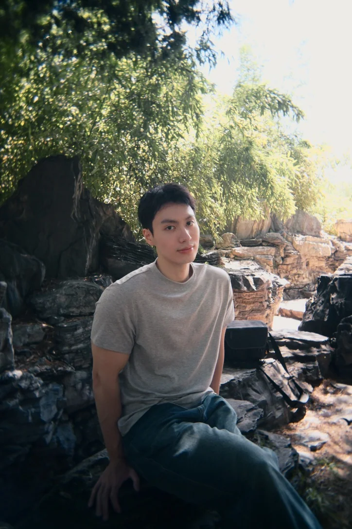 Wynn sitting among rocks beneath the trees